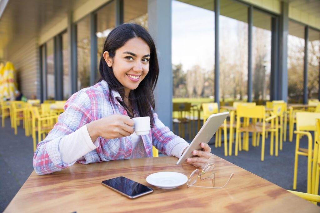 Woman sat in cafe using a vocabulary app on her iPad